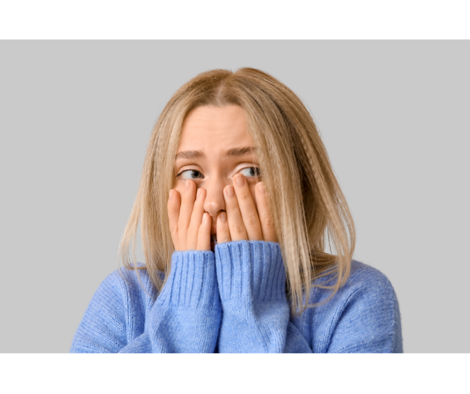 Woman holding her hands to her face worried, her eyes peering through her fingers