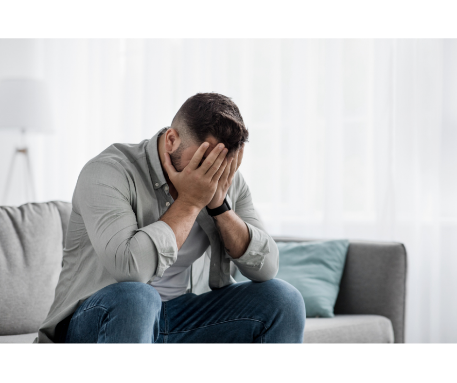 Image of a man sitting with his face in his hands in shame. Shame and Self-worth