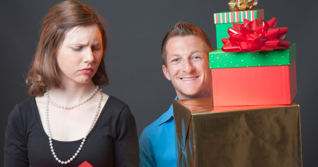 Image of a guy smiling with lots of gifts with a lady looking at him enviously with 1 gift in her hand. Why Comparison at Work Triggers Envy and How It Quietly Shapes Performance