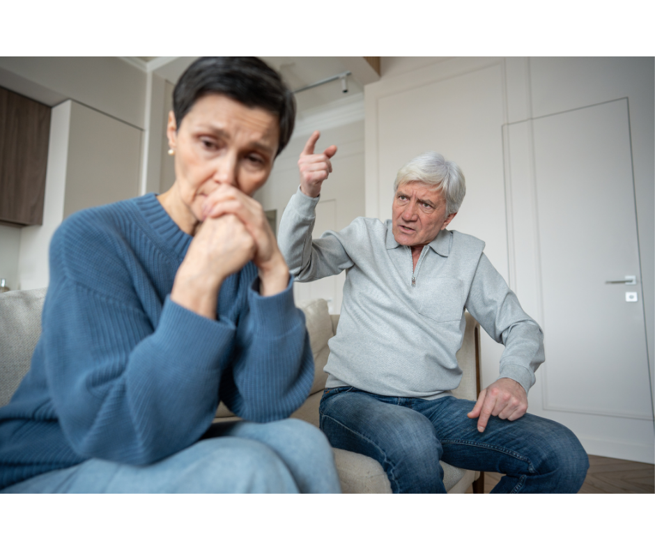 Woman looking sad in the foreground while her husband sits beside her in anger with his hands raised. Feeling unappreciated