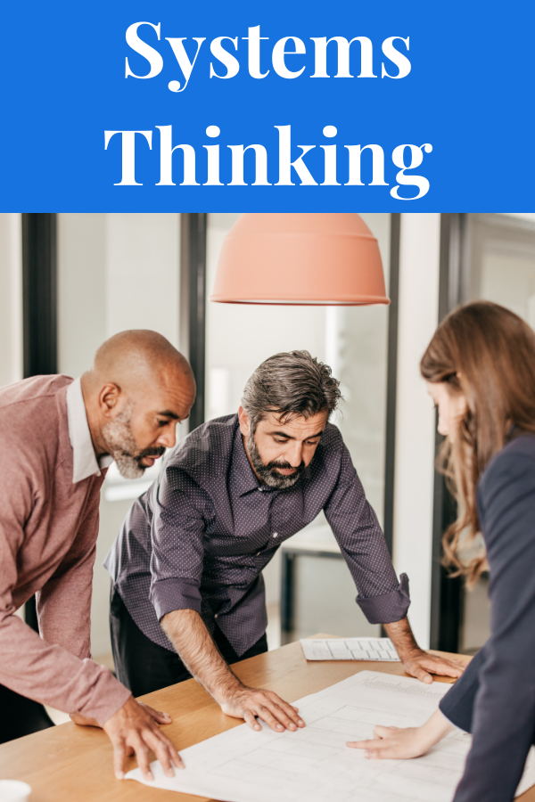 Systems Thinking articles. Image of people leaning of a table with to look at a plan