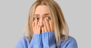 Woman holding her hands to her face worried, her eyes peering through her fingers. Overthinking and Mental Overload