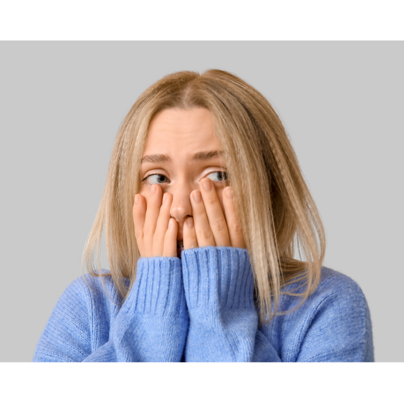 Woman holding her hands to her face worried, her eyes peering through her fingers